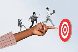 Hand pointing at a target with humans walking on top, implying guiding leads to where you want them to go in your marketing funnel