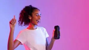Happy black lady enjoying music with speaker on dual-tone background, panorama, free space