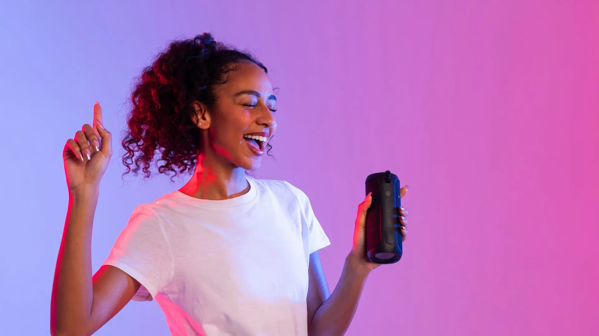 Happy black lady enjoying music with speaker on dual-tone background, panorama, free space