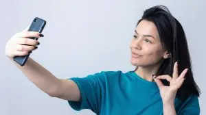 Portrait of a pretty girl taking a selfie isolated over grey background