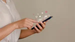 young woman using smartphone with social icon pop-up A young business woman is using a mobile phone to search the Internet for information and social media. technology concept and people