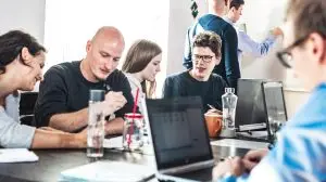 Startup business and entrepreneurship problem solving. Young AI programmers and IT software developers team brainstorming and programming on desktop computer in startup company share office space.