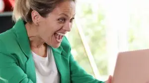 Smiling excited woman holding laptop and looking at screen with happiness