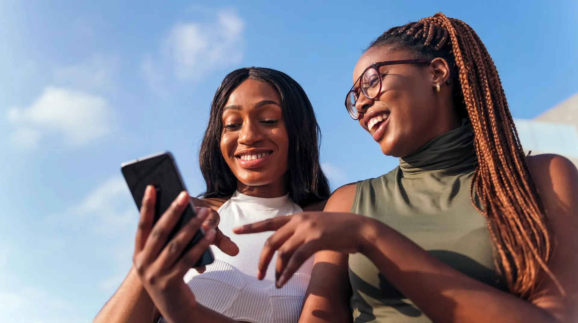 Two,Young,African,Women,Having,Fun,Looking,At,The,Cell