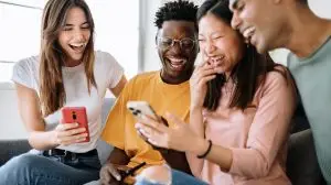 Young,Group,Of,Diverse,Friends,Sitting,On,Sofa,Using,Mobile