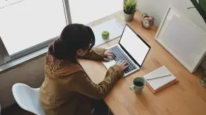 Young female freelancer typing on blank screen laptop computer