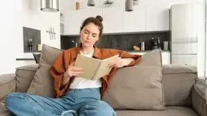 Image of woman relaxing on sofa, sitting and reading notebook, going through her notes in notepad