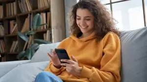 Happy,Millennial,Hispanic,Teen,Girl,Checking,Social,Media,Holding,Smartphone