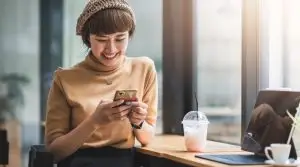 Young,Asian,Woman,Enjoying,Playing,On,Their,Phone,And,Laptop