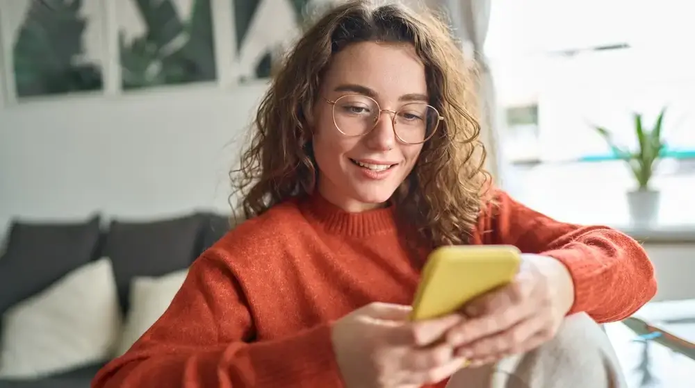 Young,Smiling,Woman,Wearing,Glasses,Holding,Smartphone,Using,Cellphone,Modern