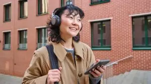 Happy,Young,Woman,Stands,On,Street,With,Backpack,And,Smartphone,