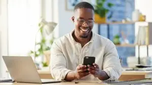 African,Business,Man,,Texting,And,Phone,In,Office,With,Smile,