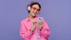 Portrait,Of,Smiling,Cute,Teenage,Woman,Wearing,Headphones,,Holding,Mobile