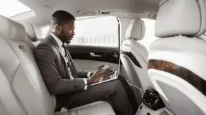 Black,Businessman,Working,On,His,Laptop,In,The,Backseat,Of