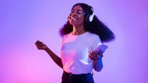 Happy,African,American,Woman,With,Headphones,And,Smartphone,Listening,To