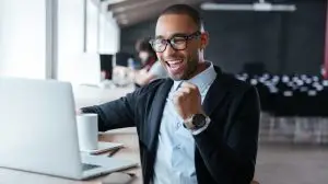 Handsome,Young,Businessman,Sitting,At,His,Ddesk,,Celebrating,Success,With
