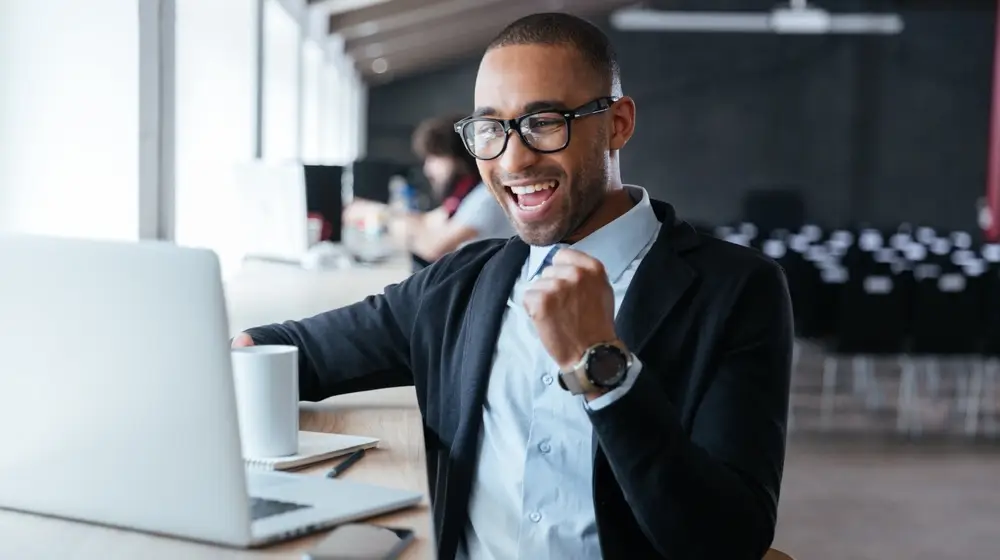 Handsome,Young,Businessman,Sitting,At,His,Ddesk,,Celebrating,Success,With