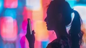 woman-holds-phone-front-colorful-light