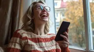 Woman laughing at phone by window