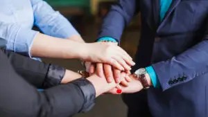 People in the office are standing holding hands together.