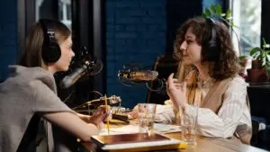 Two women are doing a podcast together. They are having a lively conversation.