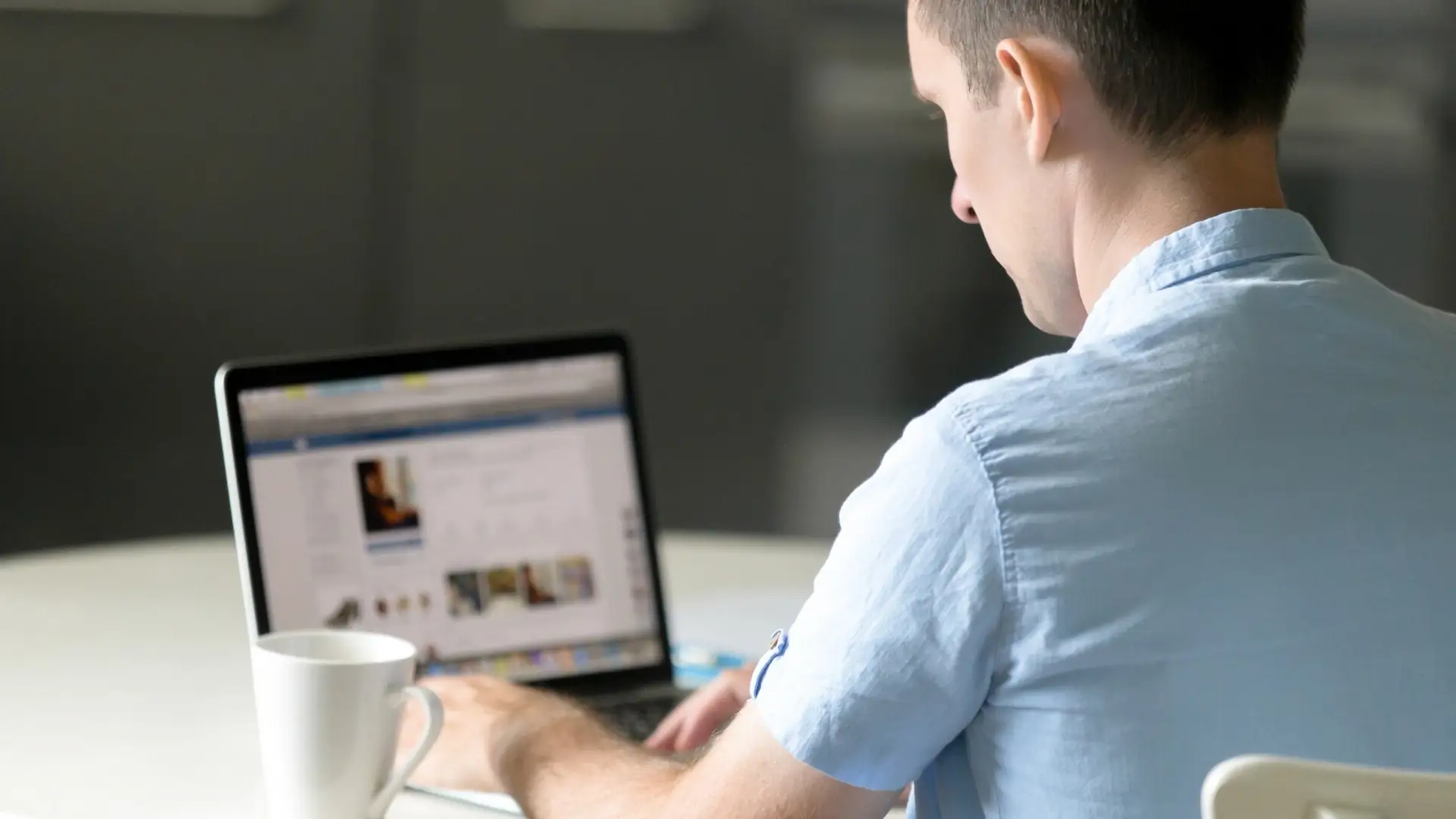 A man is behind a laptop looking at a LinkedIn page.