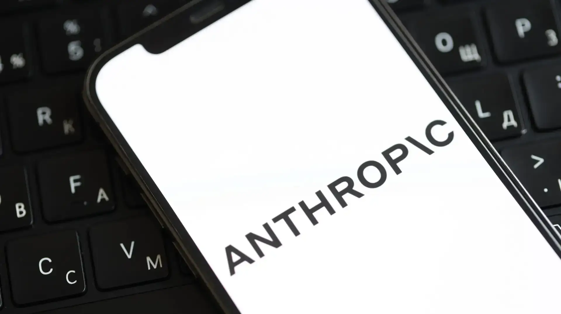 anthropic logo on an iphone with a keyboard in the background