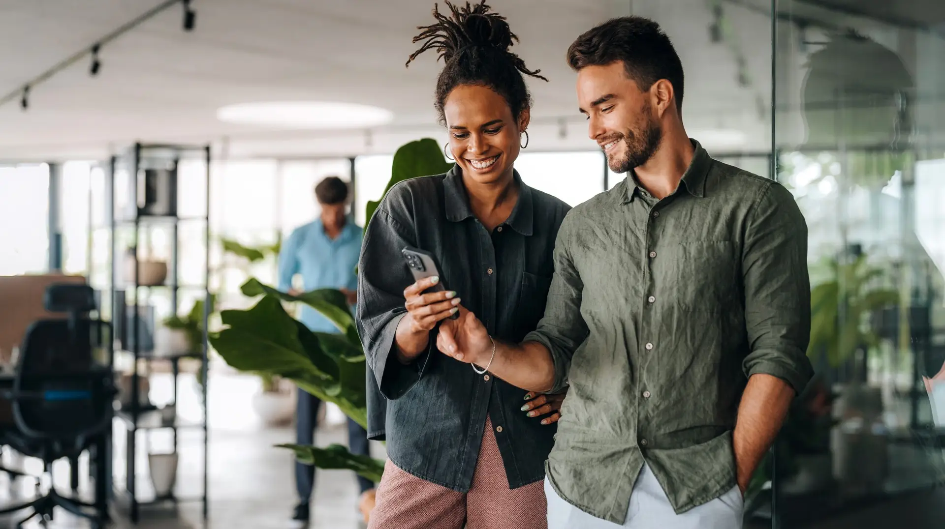 Diverse team of two business people working talking using smart phone walking in corporate office