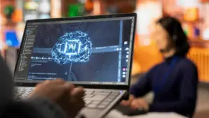 A screen with AI on it and a person working on the laptop.