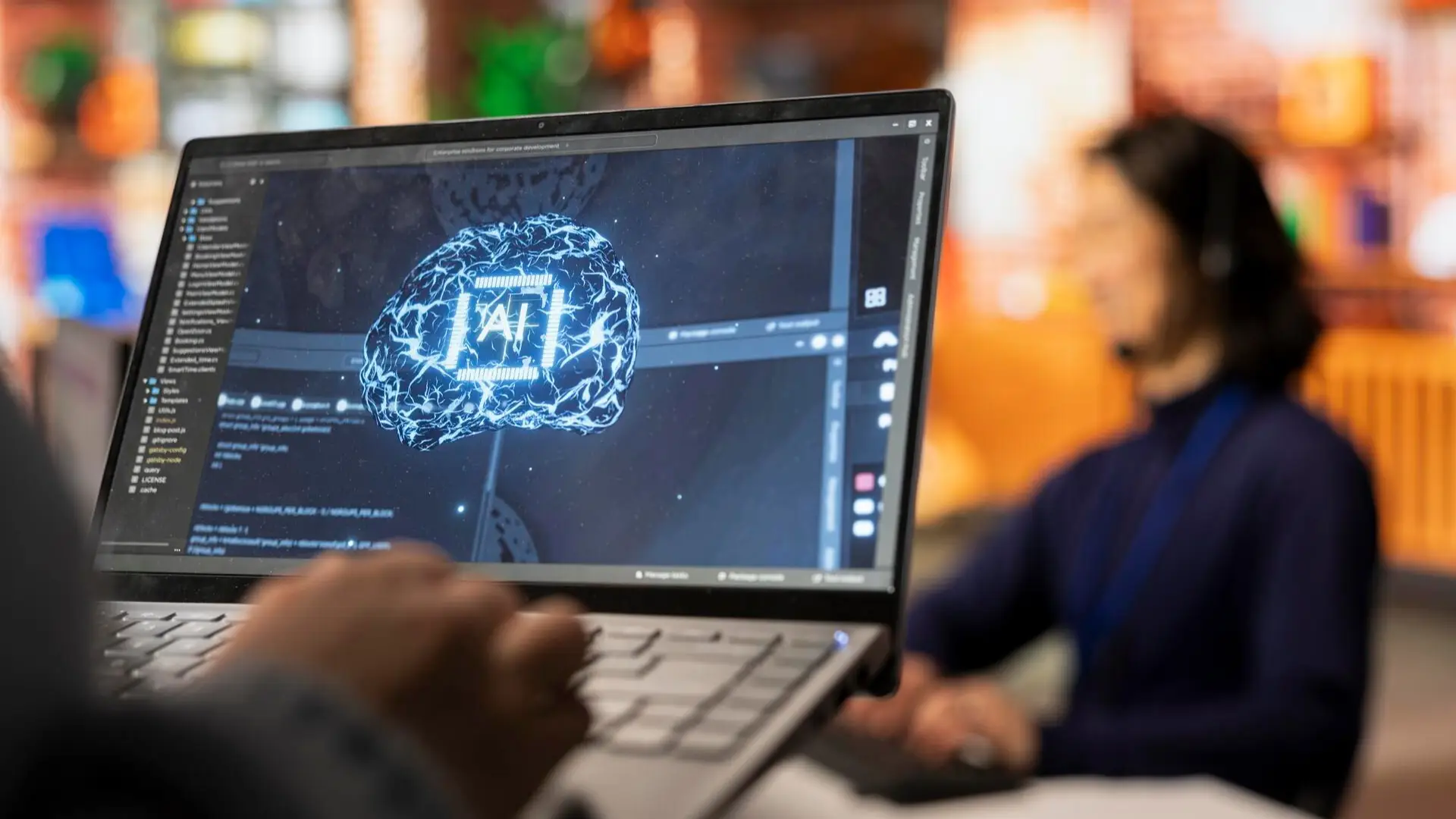 A screen with AI on it and a person working on the laptop.