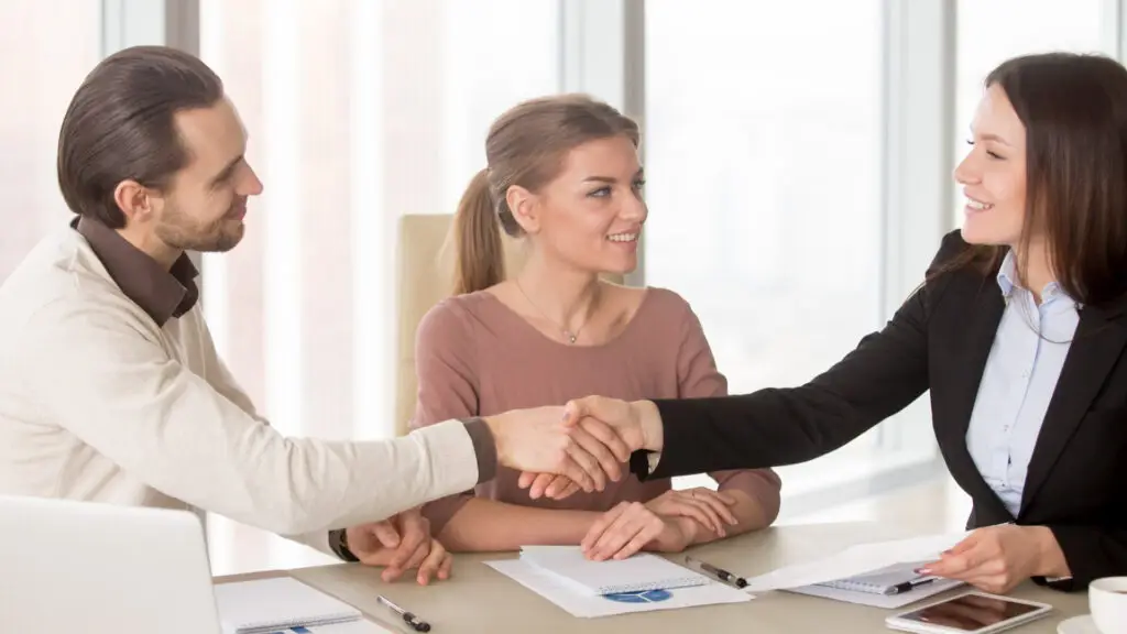 A man and a woman are shaking hands in a sign of agreement.