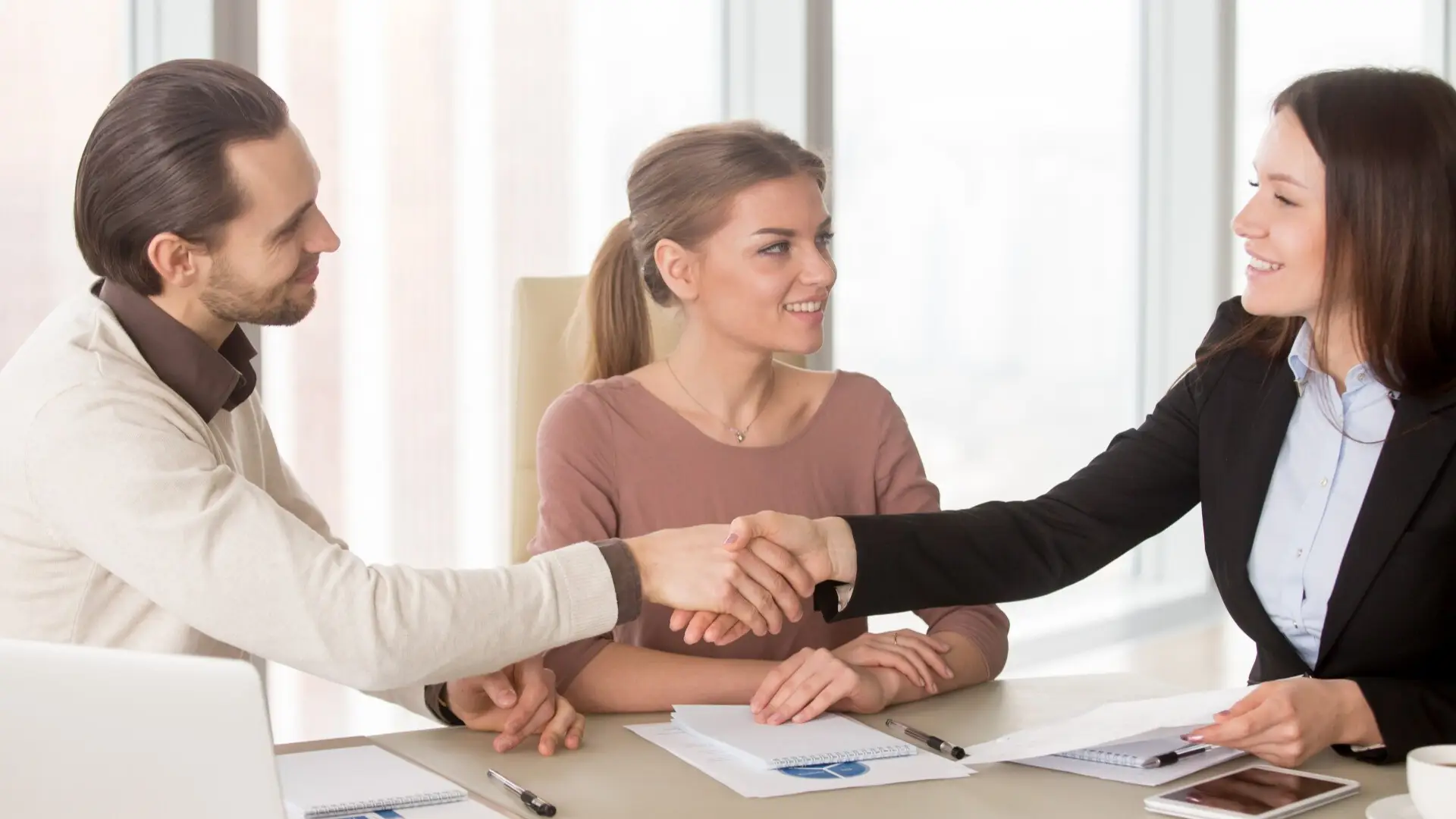 A man and a woman are shaking hands in a sign of agreement.