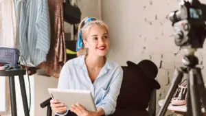 A woman is sitting in front of a camera recording content.