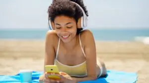 woman scrolling on reels on her phone at the beach